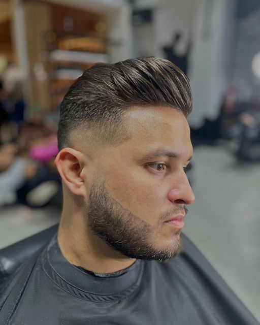 Peinado hacia atrás con degradado y barba perfilada